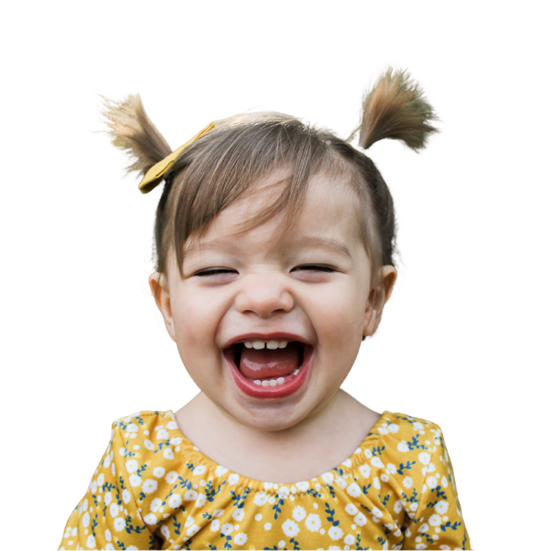 A young child with pigtails and a yellow floral dress smiles widely with their mouth open, against a plain white background.
